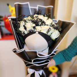 Bouquet of white roses wrapped in black paper with a white ribbon