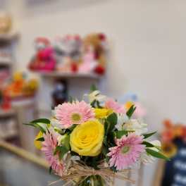 Bouquet of yellow roses and pink gerbera daisies in a glass vase
