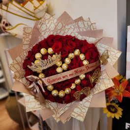 Bouquet of red roses with gold-wrapped chocolates and a decorative ribbon