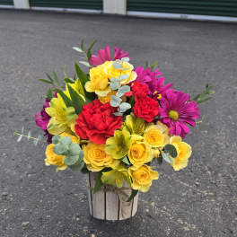 Bright mixed bouquet in a rustic wooden container