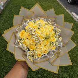 Yellow rose bouquet with small white daisies wrapped in beige paper
