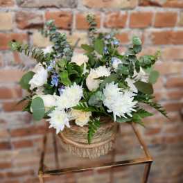 White floral arrangement in a woven basket with eucalyptus