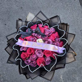 Bouquet of pink and purple roses with a black ribbon and decorative wrap