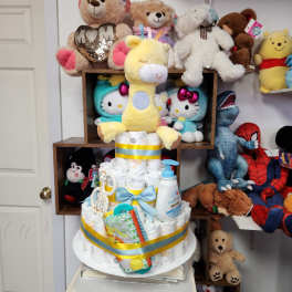 Diaper cake topped with a yellow plush giraffe and baby items