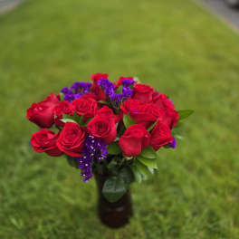 Bouquet of red roses with purple filler flowers in a vase