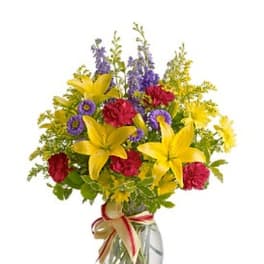Bouquet of yellow lilies, red carnations, and purple flowers in a glass vase