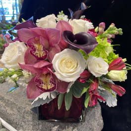 Bouquet of white roses, pink orchids, and dark calla lilies in a vase