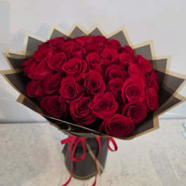Bouquet of red roses wrapped in black and gold paper with a red ribbon