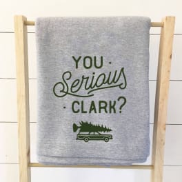 Gray folded shirt with green text on a wooden rack