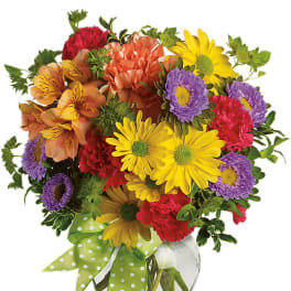 Colorful mixed bouquet in a glass vase with a green polka-dot ribbon