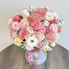 Pink and white mixed flower bouquet in a round box with ribbon