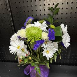 White daisies and purple flowers in a small vase with a purple ribbon