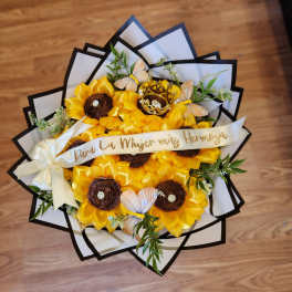 Yellow flower bouquet with butterflies and a ribbon on a wooden floor