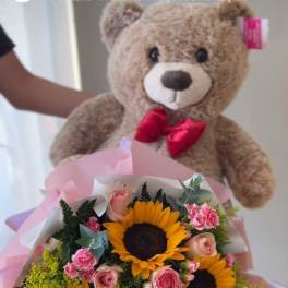 Bouquet of sunflowers and pink roses with a teddy bear