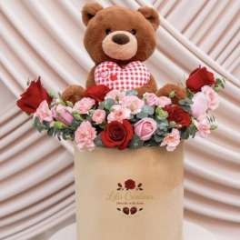 Teddy bear in a hatbox with red and pink roses