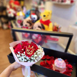 Handheld bouquet of red roses with white baby's breath and a gold crown pick