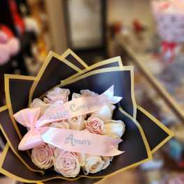 Pink and white rose bouquet wrapped in black paper with a pink ribbon
