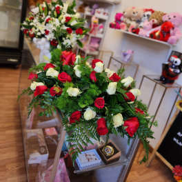 Two rose arrangements in a shop, one red and white bouquet in front and one mixed bouquet behind.