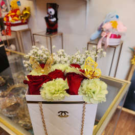 Red roses and pale green carnations in a white box with gold chain handles