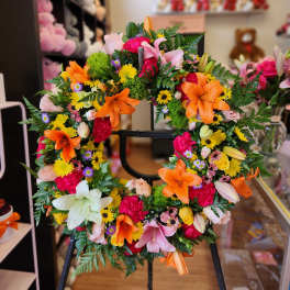 Colorful floral wreath with lilies and mixed blooms on a stand