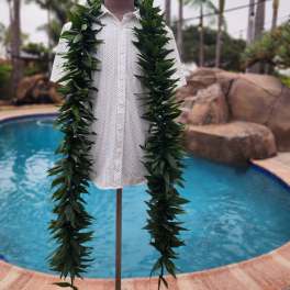 Leafy green lei draped over a white shirt on a mannequin