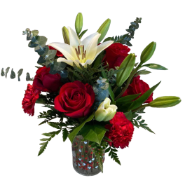 Red roses and white lilies in a heart-patterned glass vase