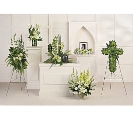 White and green funeral floral arrangements around a framed photo