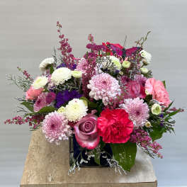 Mixed pink and white flower arrangement in a square vase with a butterfly decoration