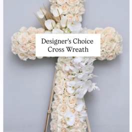 White floral cross wreath on a stand with pale roses and orchids