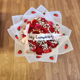 Red rose bouquet wrapped in strawberry-patterned paper with a birthday ribbon