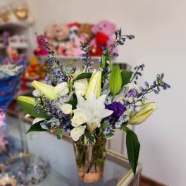 Bouquet of white lilies, white roses, and purple flowers in a glass vase