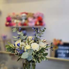 Bouquet of cream and blue flowers in a glass vase