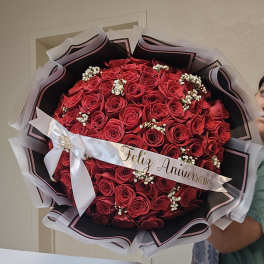 Large bouquet of red roses with a white anniversary ribbon