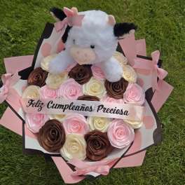 Plush cow on a bouquet of pink, cream, and brown roses with a birthday ribbon