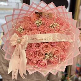 Pink rose bouquet wrapped in layered pink paper with a ribbon
