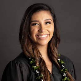 Woman in a black graduation gown wearing a floral lei