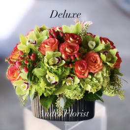 Bouquet of orange roses and green orchids in a black vase
