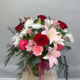 Bouquet of red roses, pink lilies, and white daisies in a glass vase