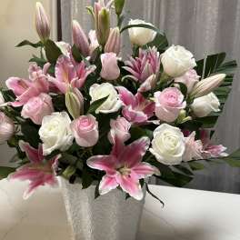 Pink lilies and white roses arranged in a textured white vase