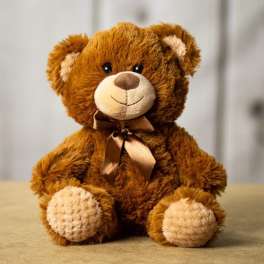 Brown teddy bear with a satin ribbon sitting on a neutral surface