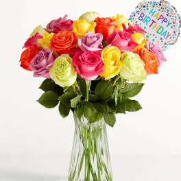 Colorful rose bouquet in a clear glass vase with a birthday balloon