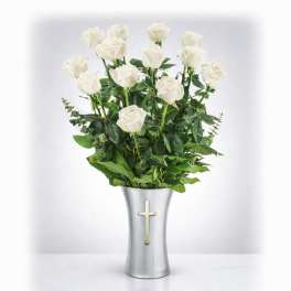 White roses in a silver vase with a cross emblem