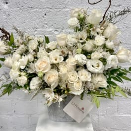 White rose and orchid arrangement in a striped container