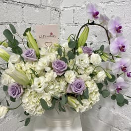 Lavender roses and white orchids in a white vase