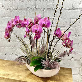 Pink orchid arrangement in a white oval bowl