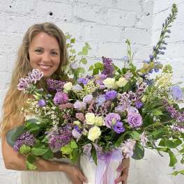 Woman holding a large lavender and white floral arrangement in a white box