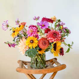 Colorful mixed bouquet in a clear glass vase on a wooden stand
