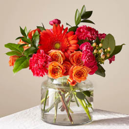 Orange and pink flowers arranged in a clear glass vase