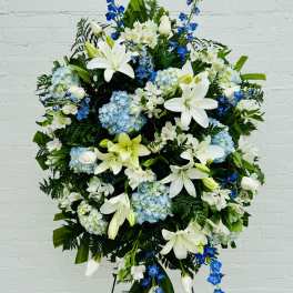 Large standing floral spray with white lilies, blue flowers, and hydrangeas
