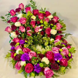 Heart-shaped floral wreath with pink, white, purple, and green blooms